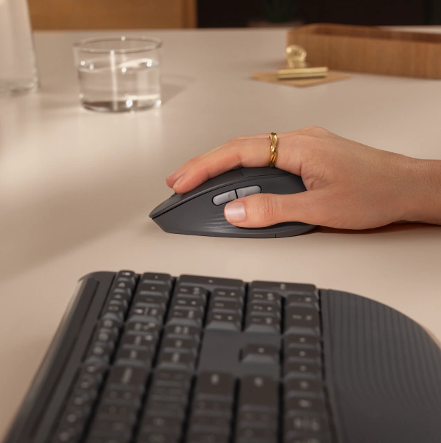Рука на миші Logitech M850L поряд із клавіатурою