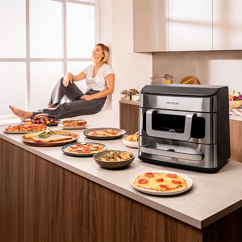 Мультипіч Cecotec Cecofry FoodCourt 18000 4Pizza+ на кухонній стільниці зі стравами та піцою