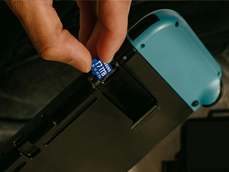 Рука вставляет карту памяти T7 microSD в портативную игровую консоль