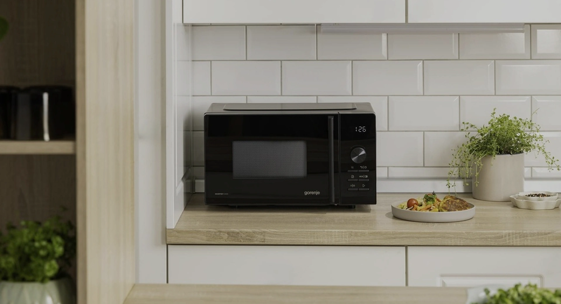 Чёрная микроволновая печь Gorenje MO20AE2B5 на кухонной столешнице