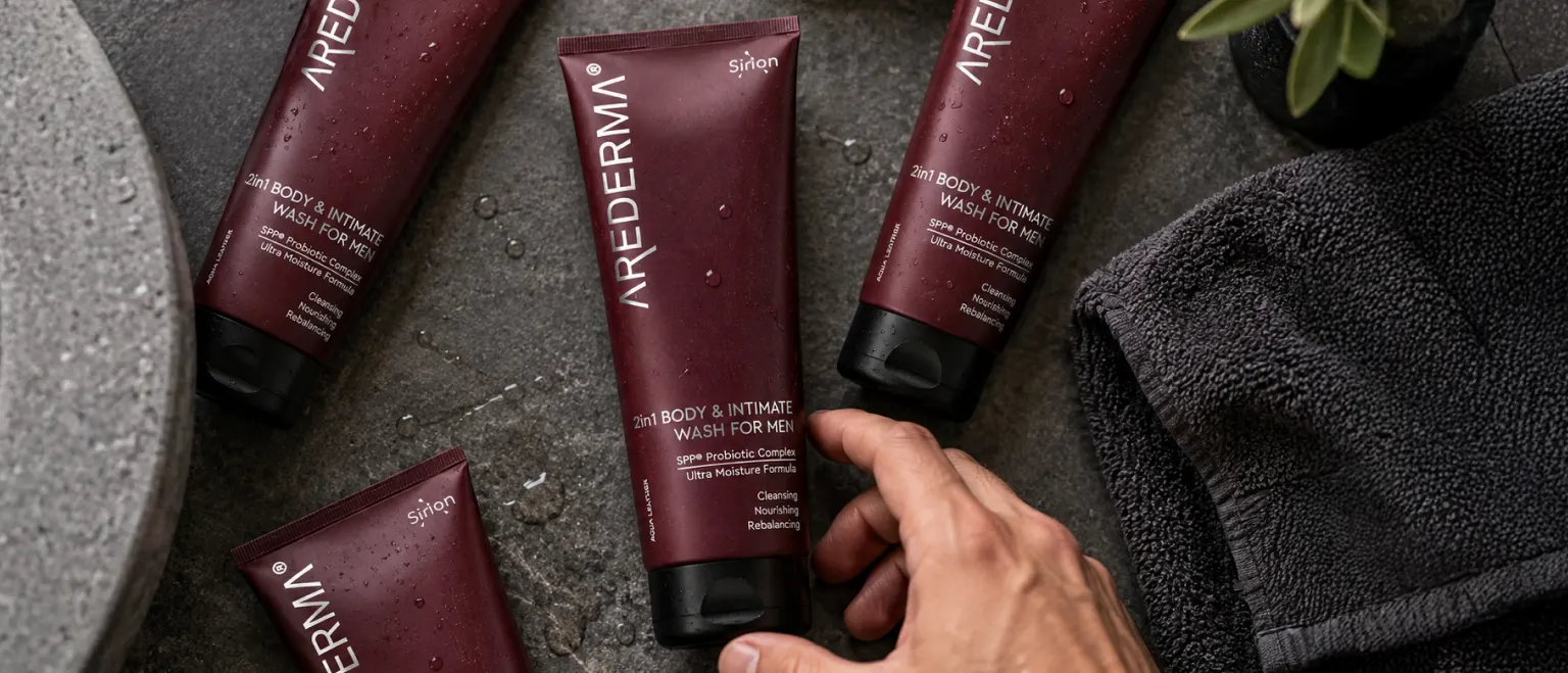Кілька флаконів гелю для душу AREDERMA Aqua Leather на стильній чорній шкіряній поверхні